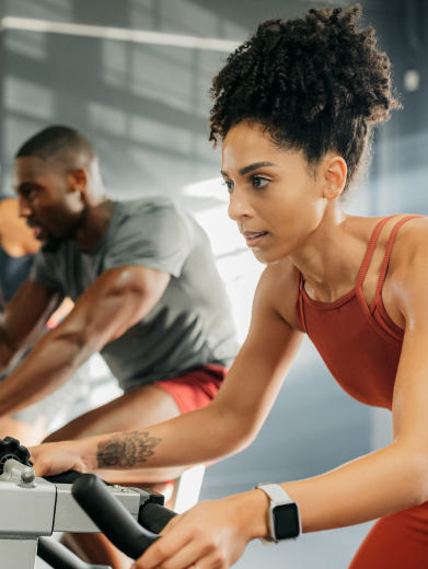 A woman rides a strationary bike to represent Astra Living's amenities