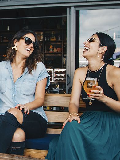 Two women enjoy drinks on a patio is the summer in downtown Calgary