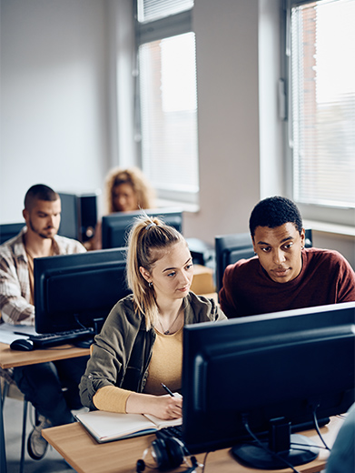 Two people work on a computer together in a coworking space